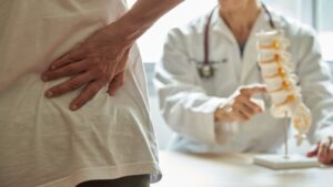 A Male Doctor Explaining Lumbar Anatomy to Female Patient Complaining of Back Pain
