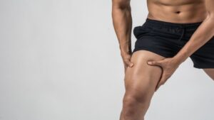 Sport Man with Strong Athletic Legs Holding the Knee with His Hands in Pain After Suffering a Ligament Injury